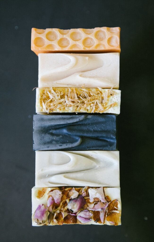 Close-up of assorted homemade organic bar soaps arranged vertically, showcasing natural textures.